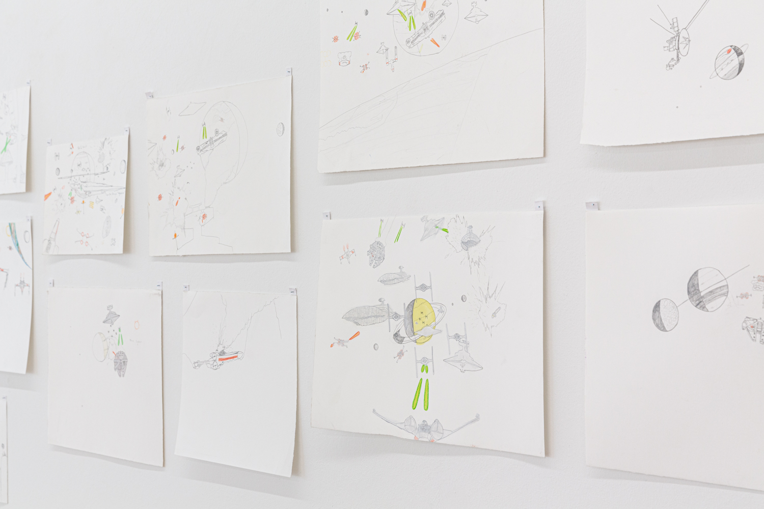 Artworks pinned to a white gallery wall