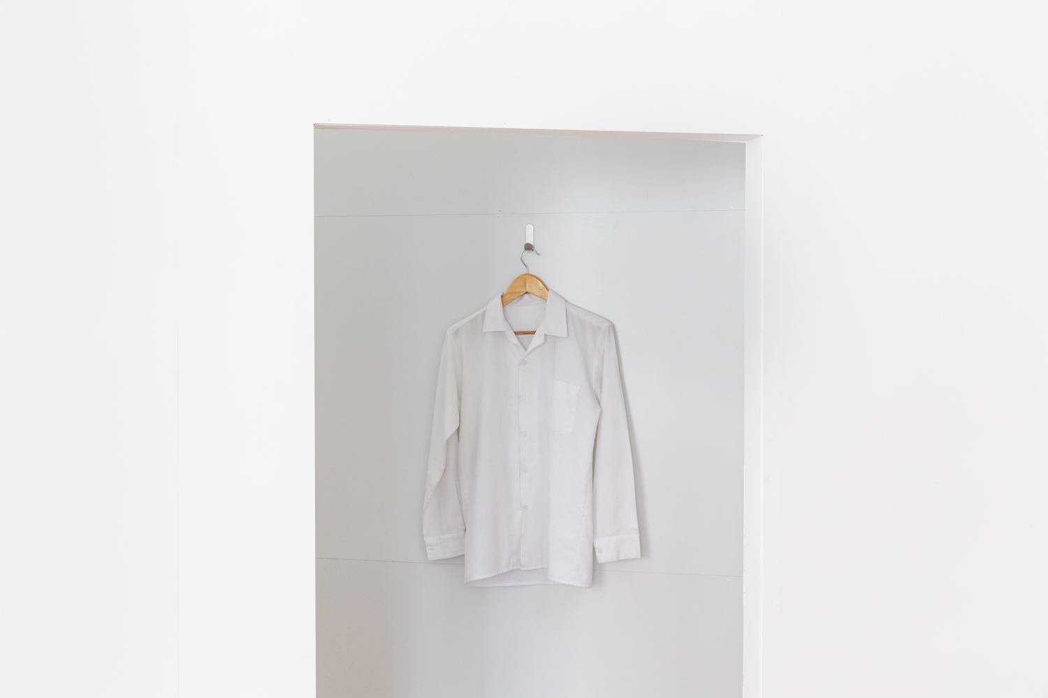 A white shirt hanging on a white wall