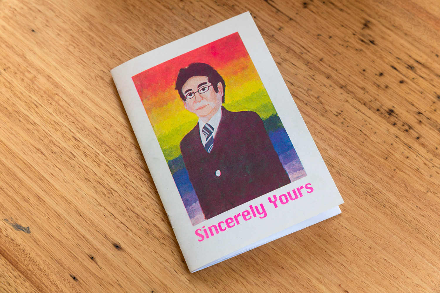 A photo of the Sincerely Yours zine laying on top of a wooden table