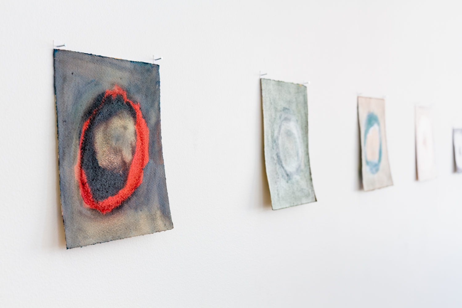 Three artworks pinned to a white gallery wall