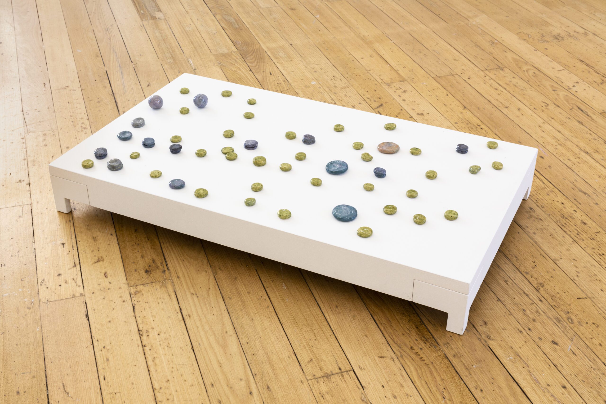 Numerous small circle ceramics displayed on a flat white surface