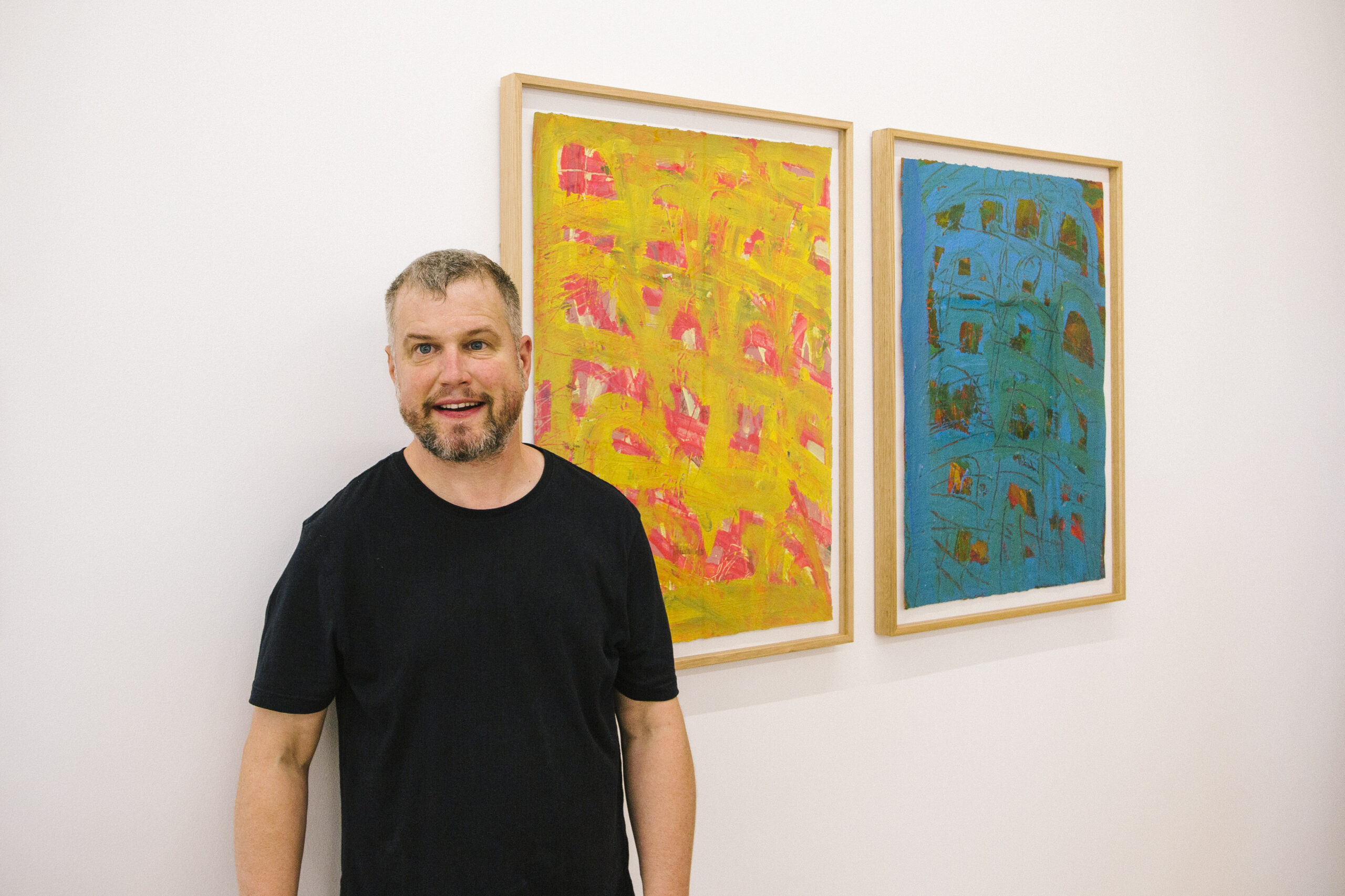Warren O'Brien standing in front of his artwork