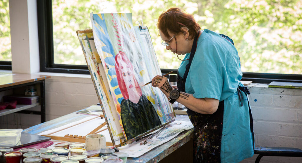 Artist Cathy Staughton painting in Arts Project Australia Northcote studio