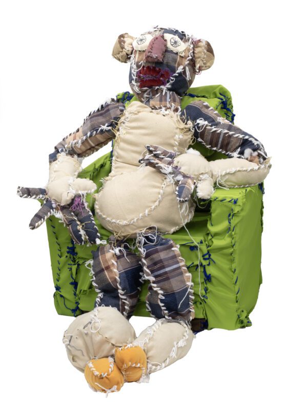 A soft sculpture of a person seated in a green arm chair