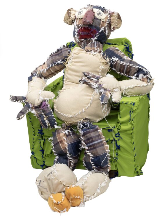 A soft sculpture of a person seated in a green arm chair