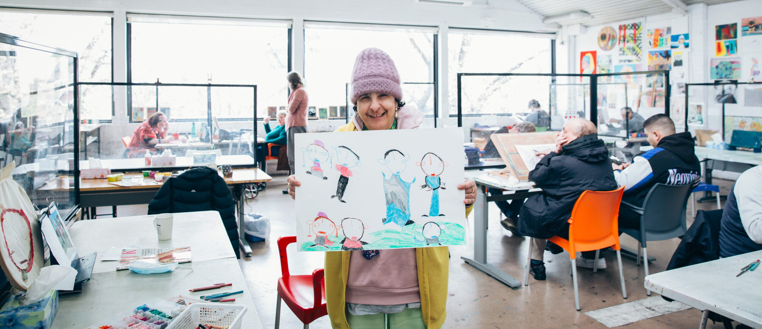 Artist Nouha Hamra in Arts Project Australia's Northcote studio holding one of their drawings