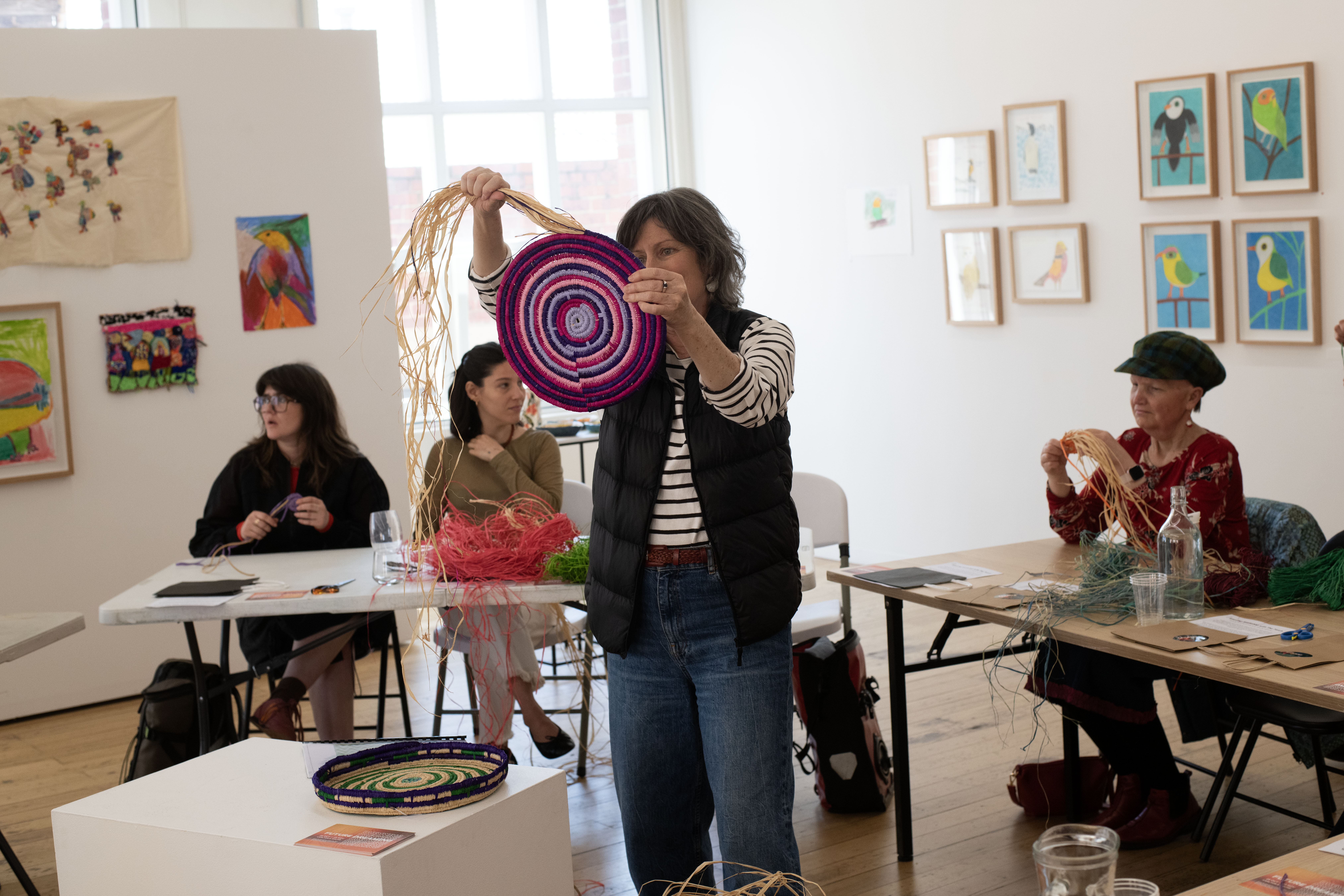 Stacey Edwards holding up her woven basket for participants to see