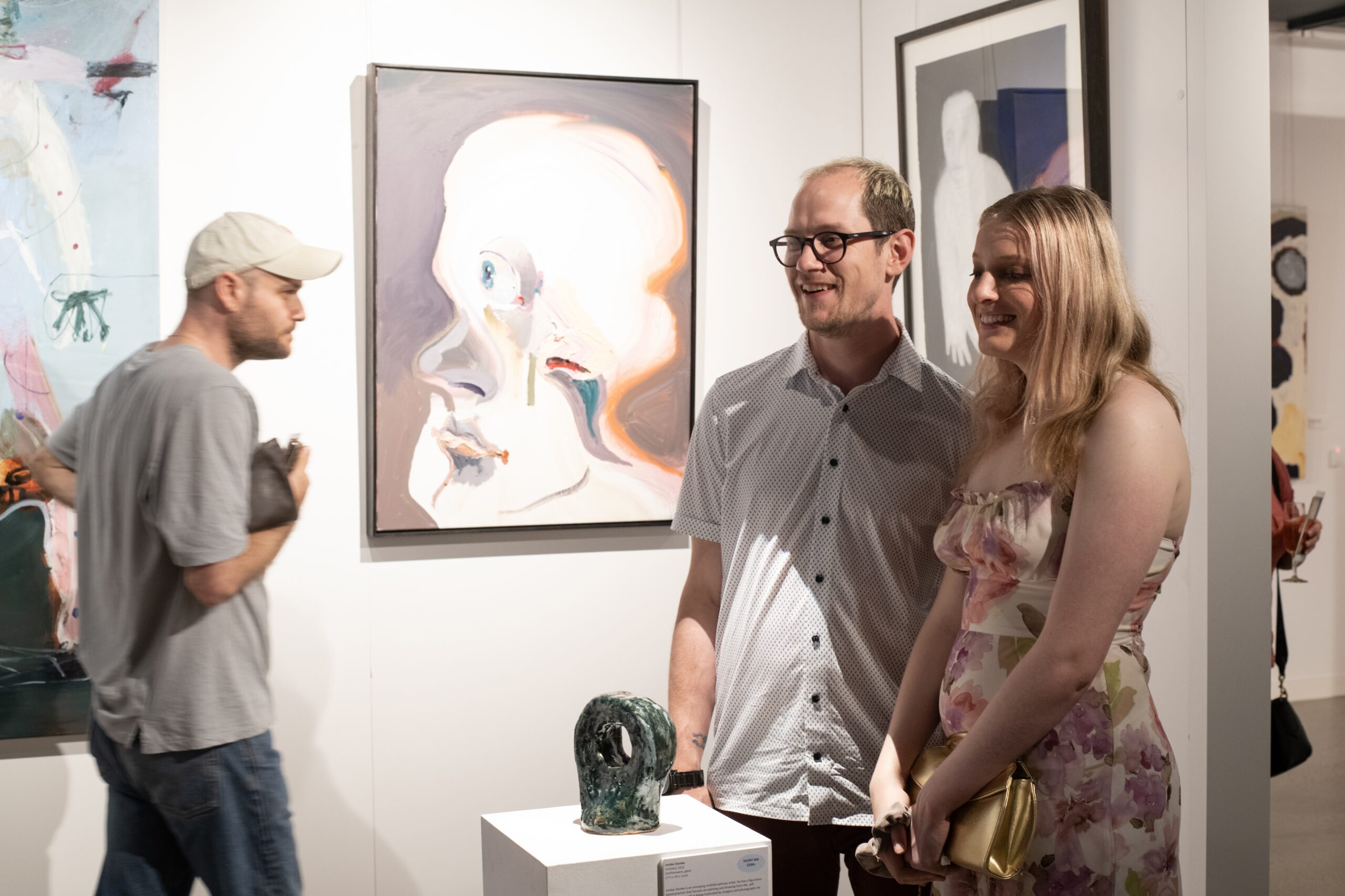 APA artist Jordan Dymke (left) is standing with his partner behind his ceramic sculpture