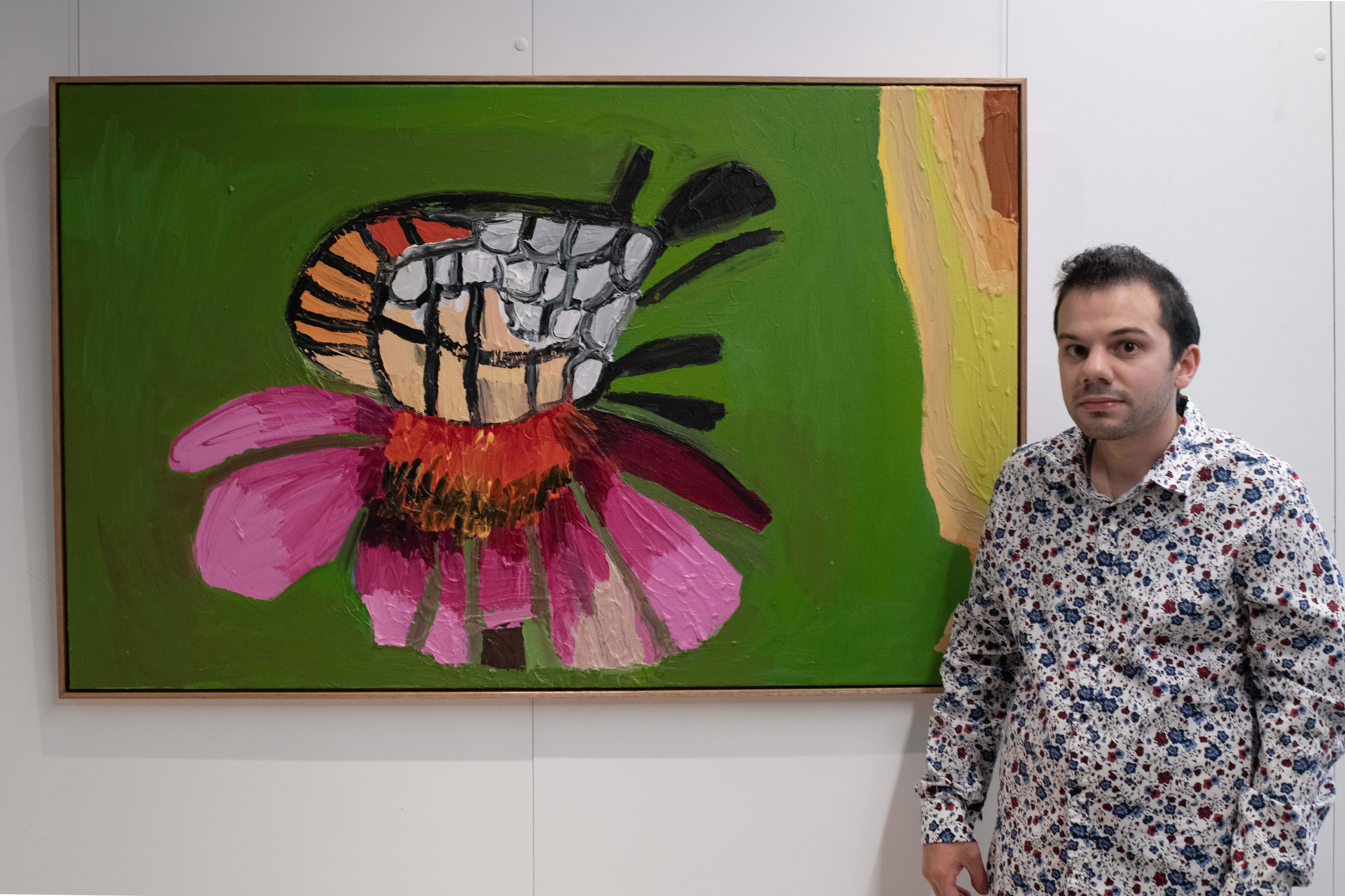 Jacob Cartelli standing in front of his abstract painting of a flower