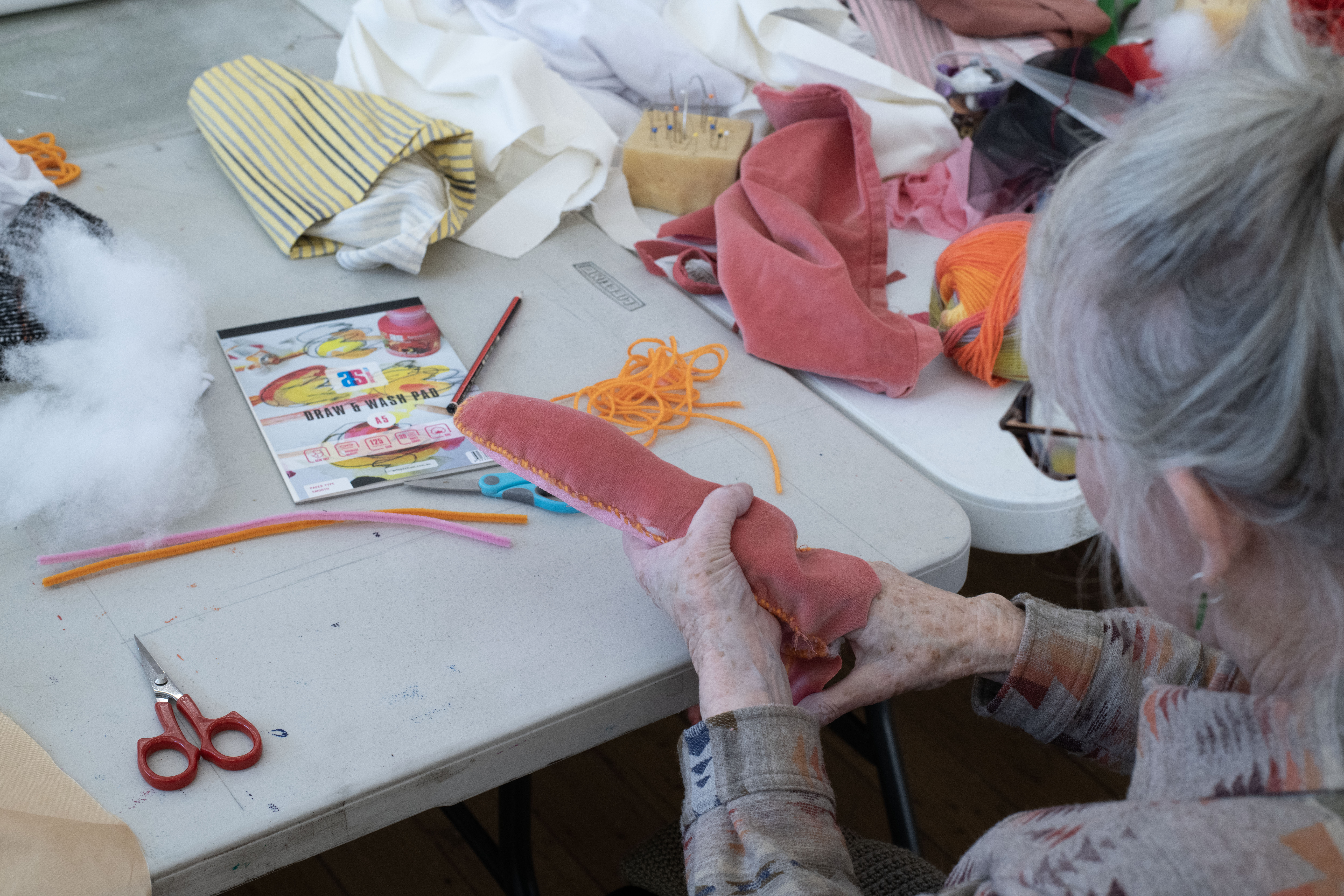 Two hands holding a pink stuffed oblong object depicting a tongue.