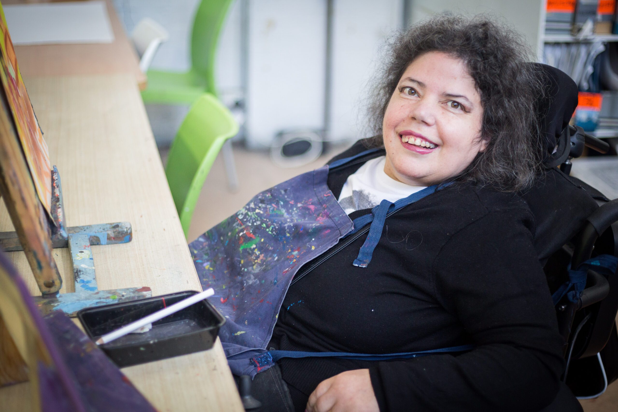Dionne working in the APA studio. She is at her desk and smiling towards the camera.