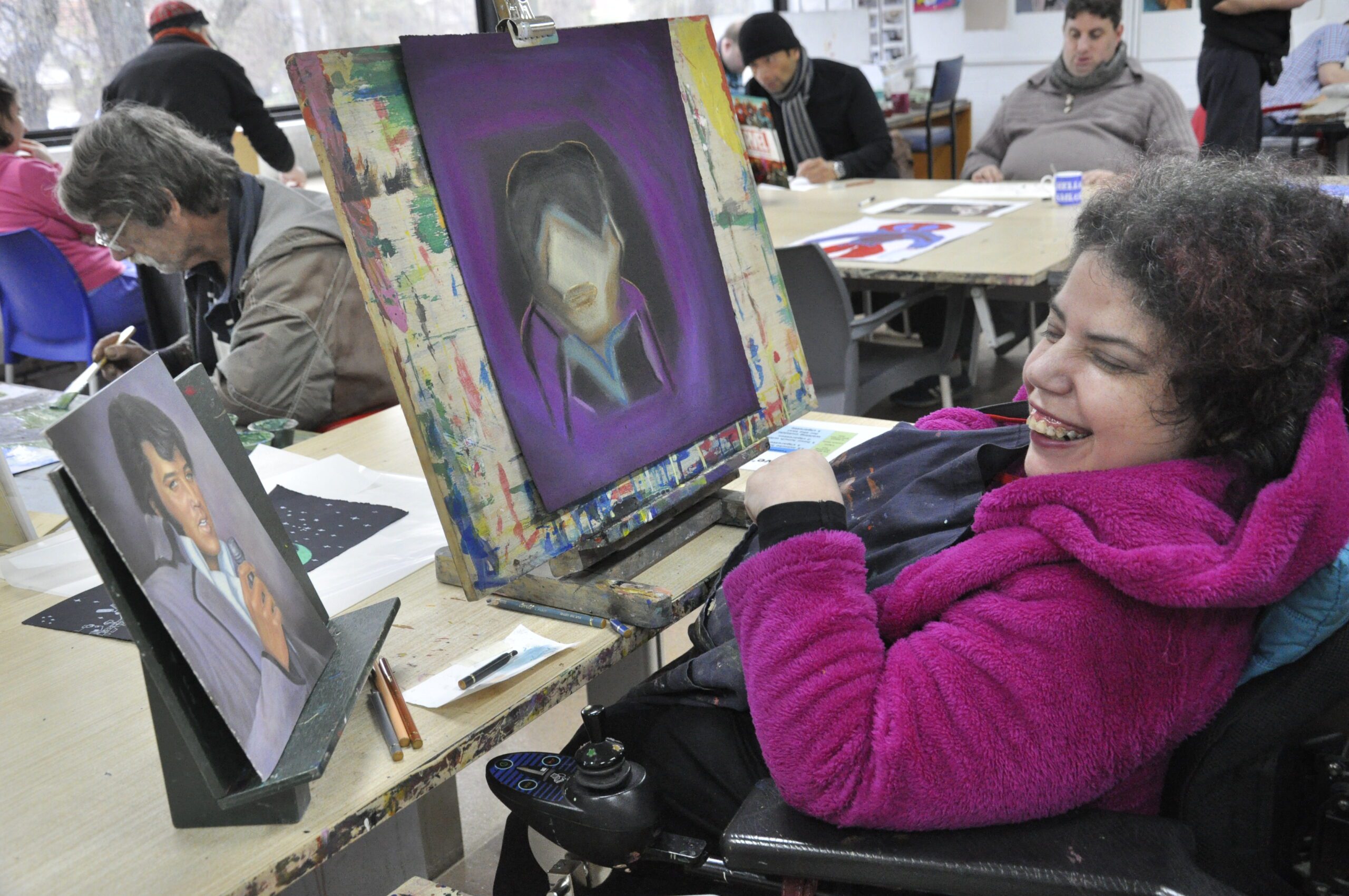 Dionne working in the APA studio. She is at her desk working on a pastel drawing.