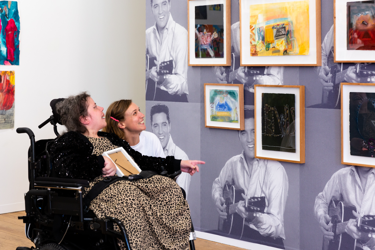 Dionne in the APA gallery with staff artist Carolyn Hawkins. They are looking at Dionne's framed artworks of Elvis Presley.