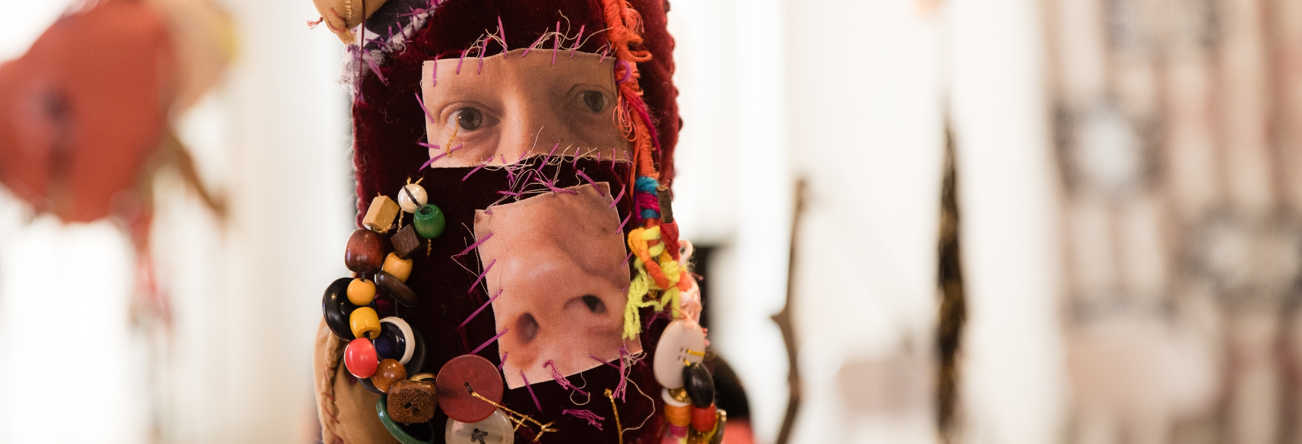 This is a photo showing the detail of a soft sculpture depicting a human heart. The artist, Bronwyn Hack has sewn an image of her eyes and nose onto the artwork.