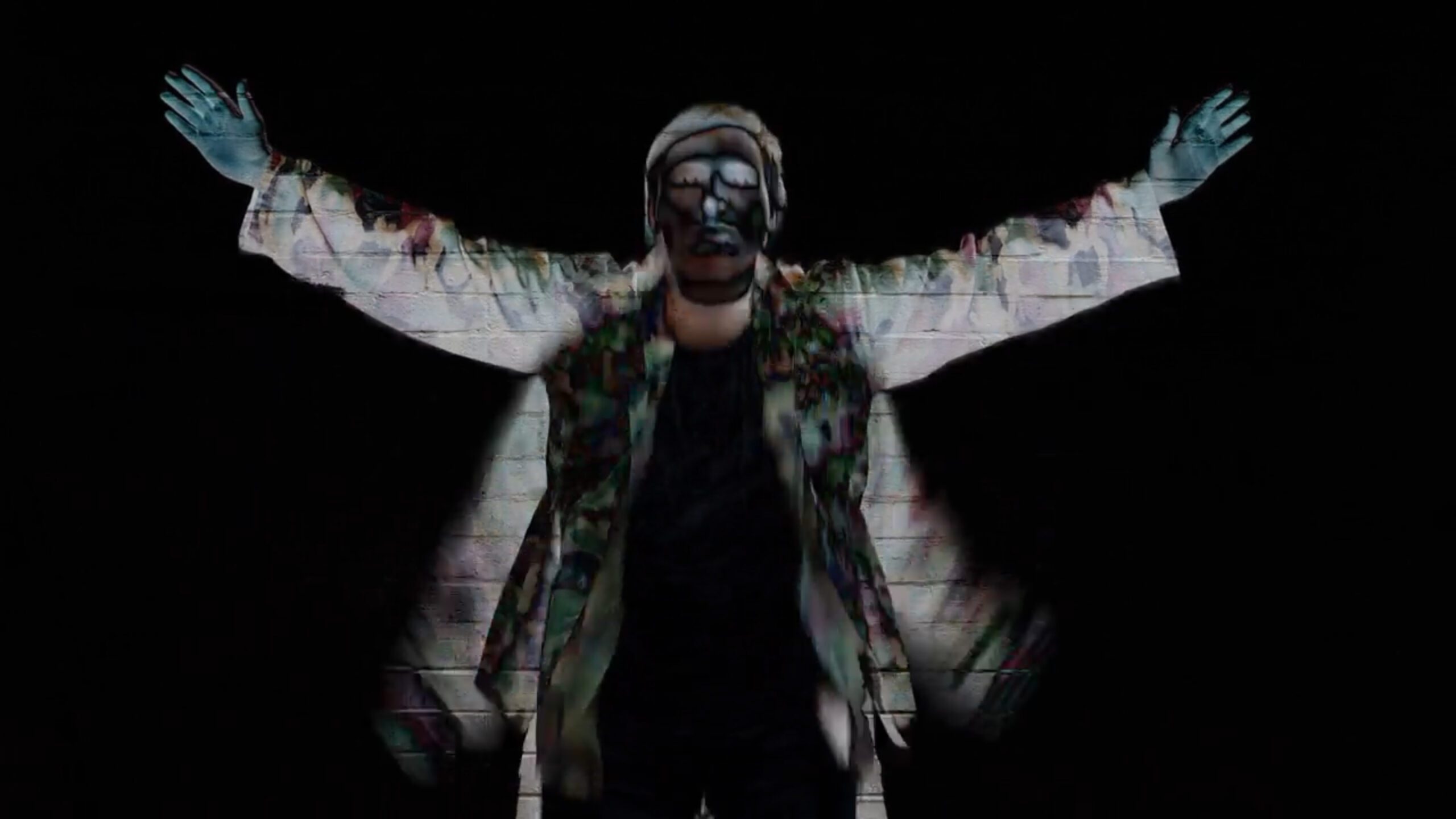 This is a photo of Max Cheevers. He is wearing a white coat covered in paint. His arms are up in the air.