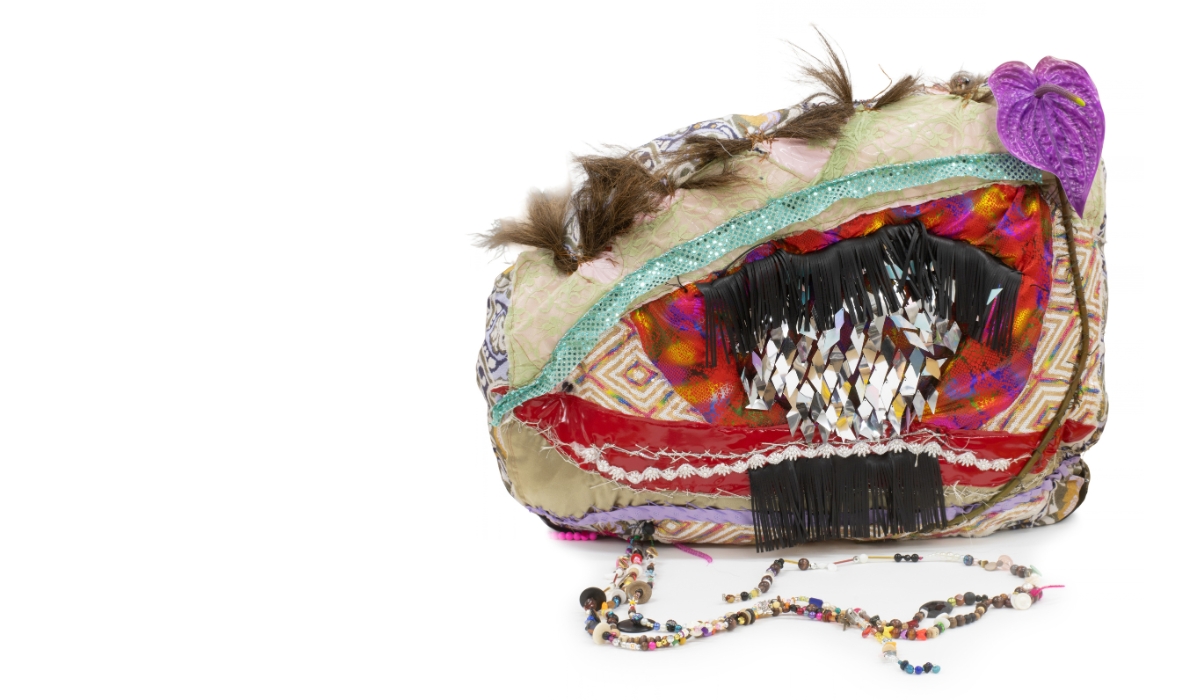 an abstract soft sculpture artwork by Bronwyn Hack. The artwork is called 'My Eyes Gone Wrong' and looks like an eye, decorated with beads and trimmings.